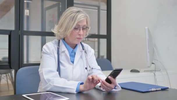 病院でスマートフォンを使用したシニア女性医師 — ストック動画
