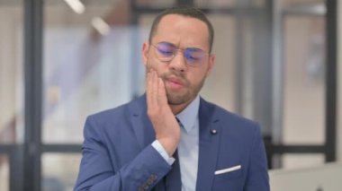 Ofisinde diş ağrısı olan rahatsız bir Karışık Irk İşadamı