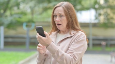 Yaşlı Yaşlı kadın dışarıda akıllı telefondan şok oldu.