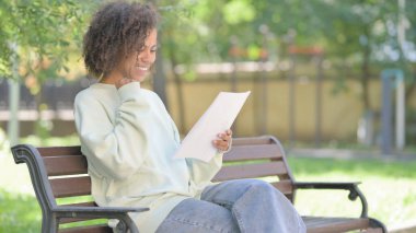 Genç Afrikalı Kadın Dışarıda Otururken Belgeleri Kutluyor ve Okurken