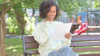 Açık havada oturup Belgeleri Kutlayan ve Okuyan Sıradan Afrikalı Kadın