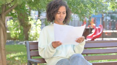 Açık havada otururken gelişigüzel Afrikalı Kadın Belgeleri Okurken