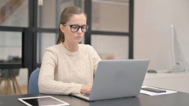 Ofiste dizüstü bilgisayarda yazan genç bir kadın.