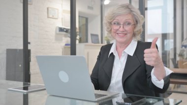 Dizüstü bilgisayar kullanırken Yaşlı İş Kadını Başparmağıyla Kaldırdı