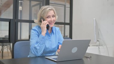 Yaşlı kadın iş için telefonda konuşuyor.