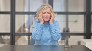 Stresli yaşlı iş kadını baş ağrısı çekiyor.