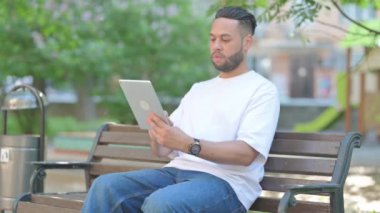 Genç adam dışarıda dijital tablet kullanıyor.