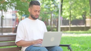 Açık havada oturan orta yaşlı adam dizüstü bilgisayarını kapattıktan sonra banktan ayrılıyor