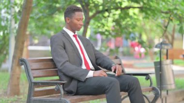 Afrikalı İşadamı Bench 'te beklerken Zamanı Denetliyor