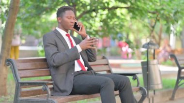Afrikalı İş Adamı Dışarıda Otururken Telefonda Konuşuyor