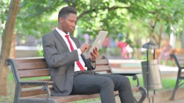 Açık havada otururken Dijital Tablet kullanan Afrikalı İşadamı