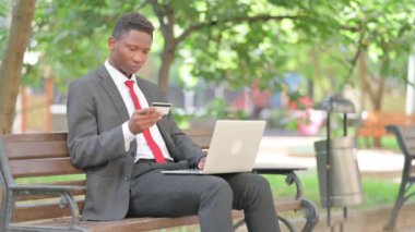 Afrikalı Adam Çevrimiçi Alışverişin Tadını Çıkartıyor Laptop ile Açık havada