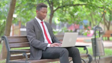 Afrikalı İşadamı kucağında dizüstü bilgisayarla kameraya gülümsüyor