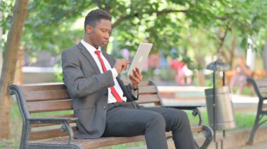 Açık havada otururken Dijital Tablet kullanan Afrikalı İşadamı