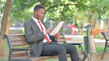 Afrikalı İşadamı Dışarıda Otururken Belgeleri Okurken