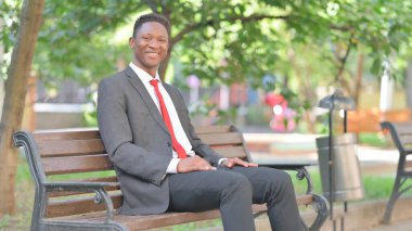 Afrikalı İşadamı Dışarıda otururken Kameraya Gülümsüyor