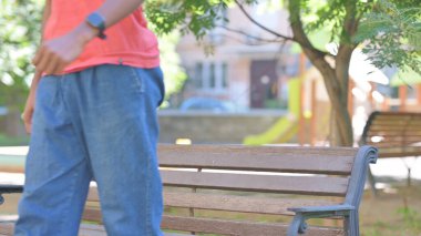 Sıradan Afrikalı Adam Bench 'te dışarıda oturduktan sonra gidiyor.