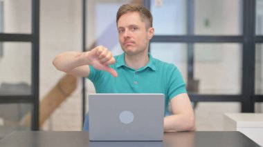 Dizüstü bilgisayarda çalışırken kameraya bakan Başparmaklı Olgun Yetişkin Adam