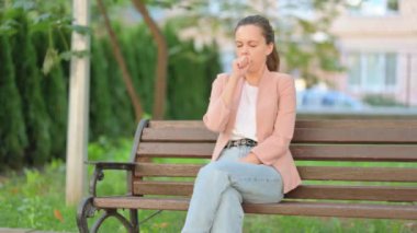 Bankta otururken sıradan bir iş kadını öksürüyor.