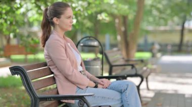 Sıradan bir iş kadını Bench Outdoor 'da otururken kameraya gülümsüyor