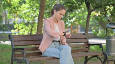 Genç Kadın Park 'ta otururken Akıllı Saat Kullanıyor