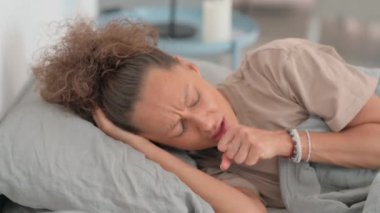 Hasta yaşlı adam yatakta yatarken öksürüyor.