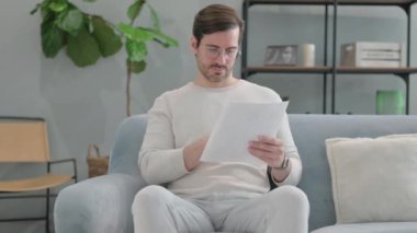 Yaşlı kıdemli adam yatakta otururken belge okuyor.