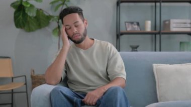 Evdeki koltukta oturan baş ağrısı olan İspanyol adam.