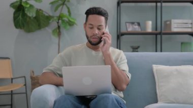 Kızgın İspanyol adam telefonda dizüstü bilgisayarla konuşuyor.