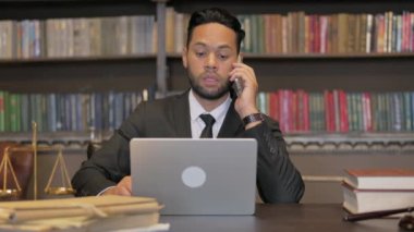 İspanyol yargıç telefonda dizüstü bilgisayarla konuşuyor.