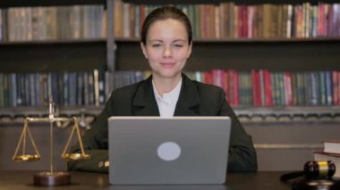 Genç bayan yargıç laptopta görüntülü sohbet yapıyor.