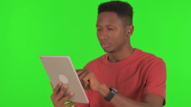 Casual African Man Using Digital Tablet on Green Background