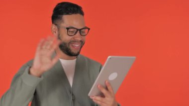 Günlük İspanyol Adam Kırmızı Arkaplanda Tablet 'te Video Sohbeti Yapıyor