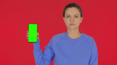 Kırmızı Arkaplanda Yeşil Ekranlı Sıradan Genç Kadın Akıllı Telefonu Gösteriyor