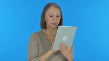 Yaşlı Kadın Mavi Arkaplanda Tablet 'te Başarıyı Kutluyor