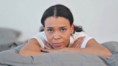 Ciddi Afrikalı Kadın Yatakta Karın üstü yatarken Kameraya Bakıyor