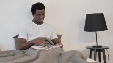 Afrikalı Adam Yatakta Otururken Kitap Okuyor