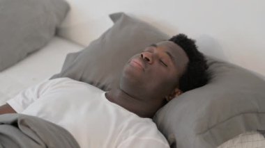 Afrikalı adam uyanıyor ve yataktan kalkıyor.