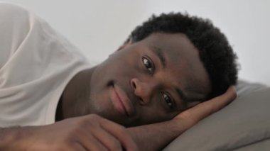 Yatakta yatan gülümseyen Afrikalı adama yaklaş.