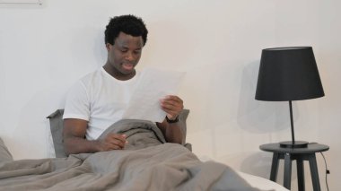 Yatakta Otururken Belgeleri Okuyan Afrikalı Adam