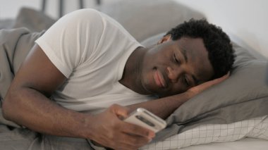 Afrikalı Adam Yatakta Yatarken Akıllı Telefon Kullanıyor