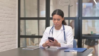 Hastanede akıllı telefon kullanan Afrikalı kadın doktor.