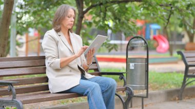 Yaşlı Kadın Bench 'te otururken Dijital Tablet Kullanıyor