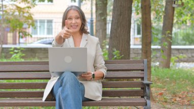 Park 'ta Dizüstü bilgisayar kullanan Yaşlı Yaşlı Kadın Başparmağını kaldırdı