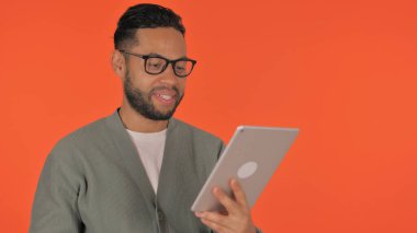 Günlük İspanyol Adam Kırmızı Arkaplanda Tablet 'te Video Sohbeti Yapıyor