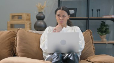 Kucağında dizüstü bilgisayarla bilek ağrısı çeken Afrikalı kadın.