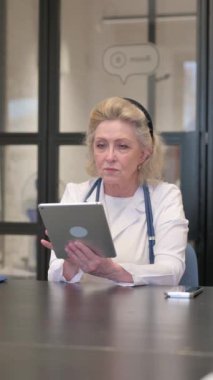 Hastanede çalışmak için dijital tablet kullanan kıdemli kadın doktor.