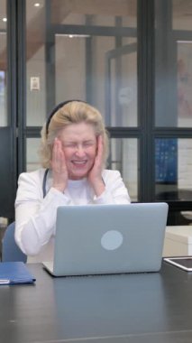 Çalışan yaşlı kadın doktor klinikte baş ağrısı çekiyor.