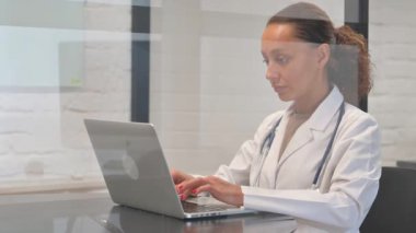 Dizüstü bilgisayarda yazan çok ırklı kadın doktor.