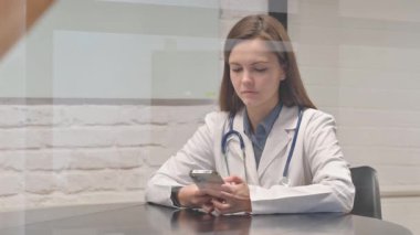 Genç Kadın Doktor İş yerinde Telefonu Kullanıyor